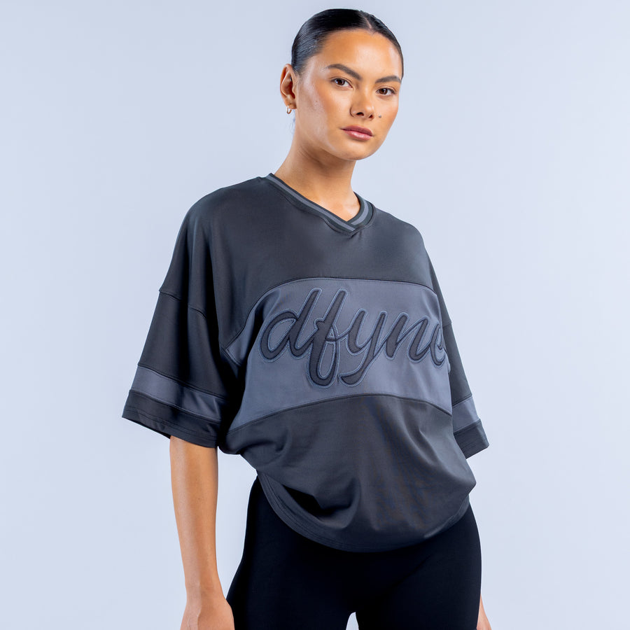 Dark short-sleeve V-neck top with large cursive logo print at center chest