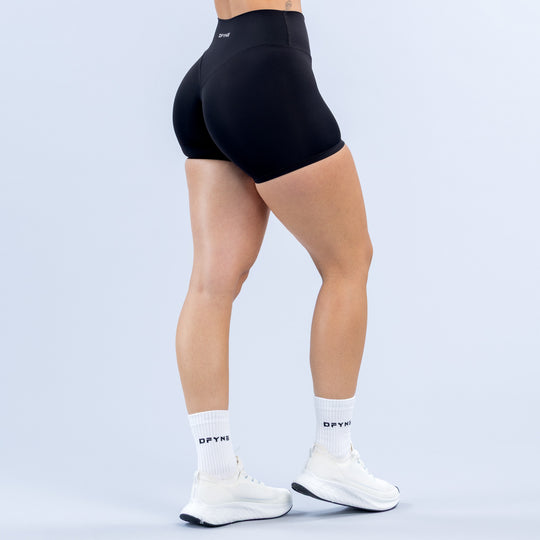 Women's black 4.5" biker shorts, back view, sculpting seams and elastic waistband