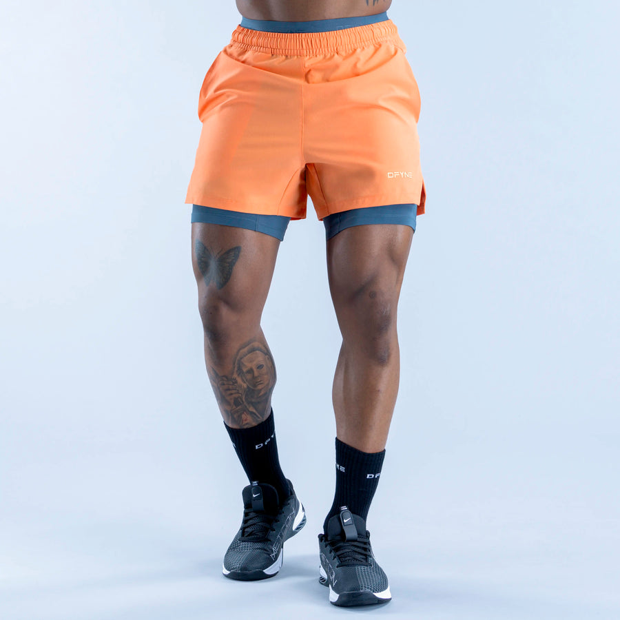Unbound baselayer shorts in orange, form-fitting with waistband and stitched seams