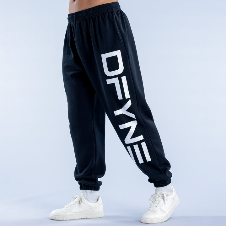 Dark cuffed jogger pants, elastic waist, white logo print on one leg