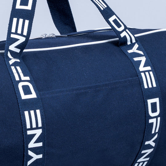 Navy duffle bag close-up with white logo strap and zipper pocket front