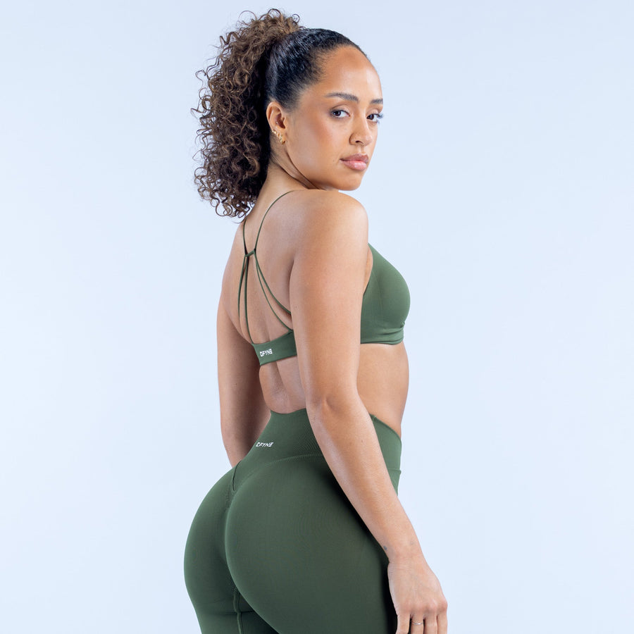 Green twist-front sports bra with thin back straps and DPYNE logo patch.